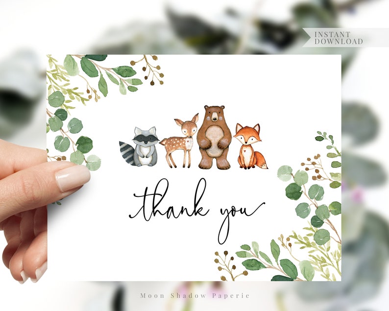May include: A white thank you card with a green leafy border. The card features a watercolor illustration of a raccoon, a deer, a bear, and a fox. The text "thank you" is written in black cursive.