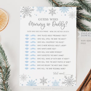 May include: A printable baby shower game card titled "Guess Who Mommy or Daddy?" with a snowflake theme. The card features questions about the parents-to-be, with space for answers. The design includes blue and gray snowflakes and text.