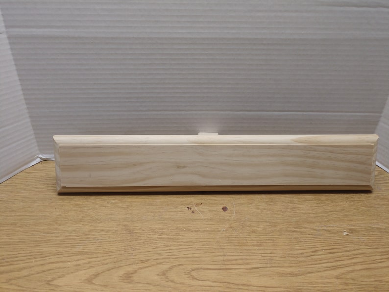 May include: A plain, unfinished wooden plaque with rounded edges. The plaque is made of light-colored wood and has a smooth surface.