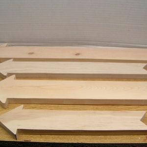 May include: Four unfinished wooden arrows of varying sizes, pointing to the right. The arrows are made of light-colored wood and have a smooth, natural finish.
