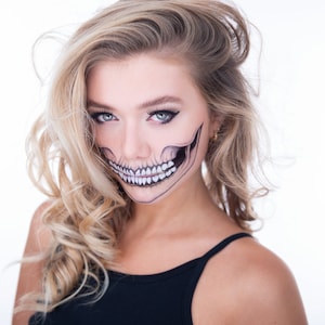 May include: A woman with blonde hair and a skull makeup design on her face. She is wearing a black tank top.