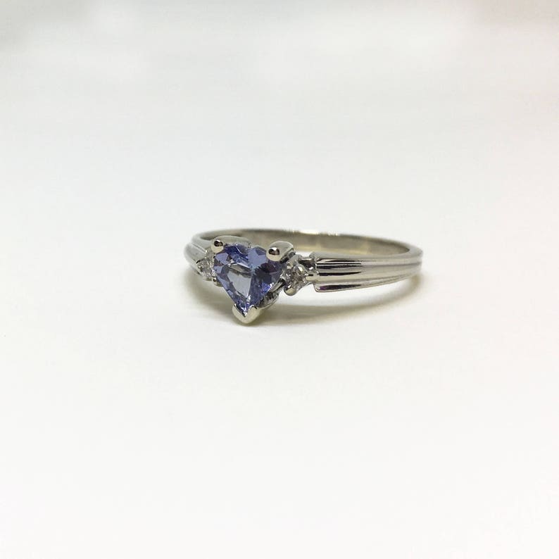 K&ouml;nnte beinhalten: Ein silberner Ring mit einem herzf&ouml;rmigen blauen Saphir und zwei kleineren Diamanten.