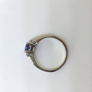 K&ouml;nnte beinhalten: Ein silberner Ring mit einem violetten Edelstein und zwei kleineren klaren Edelsteinen.