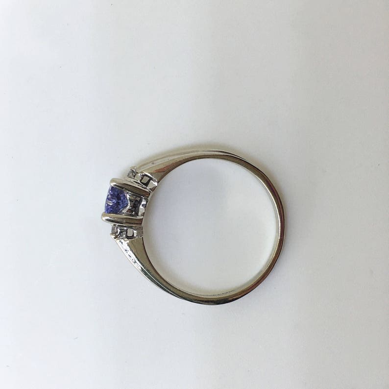 K&ouml;nnte beinhalten: Ein silberner Ring mit einem violetten Edelstein und zwei kleineren klaren Edelsteinen.