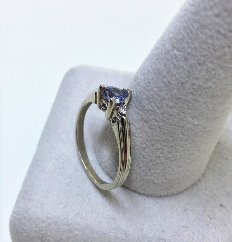 K&ouml;nnte beinhalten: Ein silberner Ring mit einem birnenf&ouml;rmigen violetten Edelstein und zwei kleineren runden Diamanten.