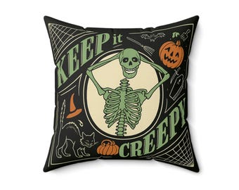 May include: Square black Halloween throw pillow with a green skeleton illustration holding its skull. The pillow features the text "KEEP IT CREEPY" in green and white, along with a black cat, pumpkin, and witch's hat.