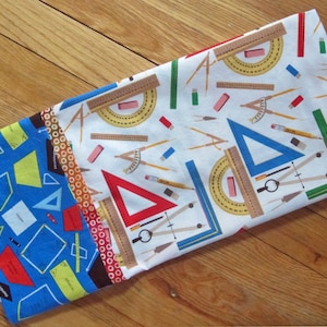May include: A set of three fabric panels with a geometric pattern. The panels feature a white background with colorful geometric shapes, including triangles, rulers, protractors, and compasses. The panels are perfect for quilting, sewing, or crafting projects.