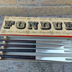 May include: A set of four fondue forks with wooden handles in a box labelled "Ambass-Fondueforks" and "Fondue".