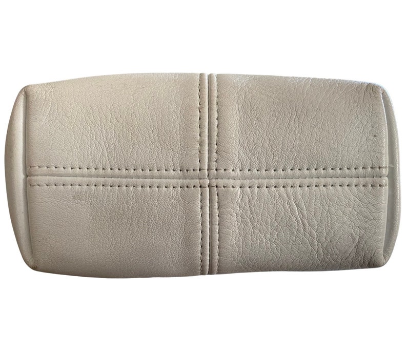 May include: A light gray leather handbag with a stitched design. The bag has a rectangular shape and a smooth, textured surface.