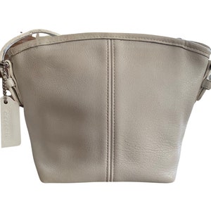 May include: A white leather shoulder bag with a Coach logo tag.