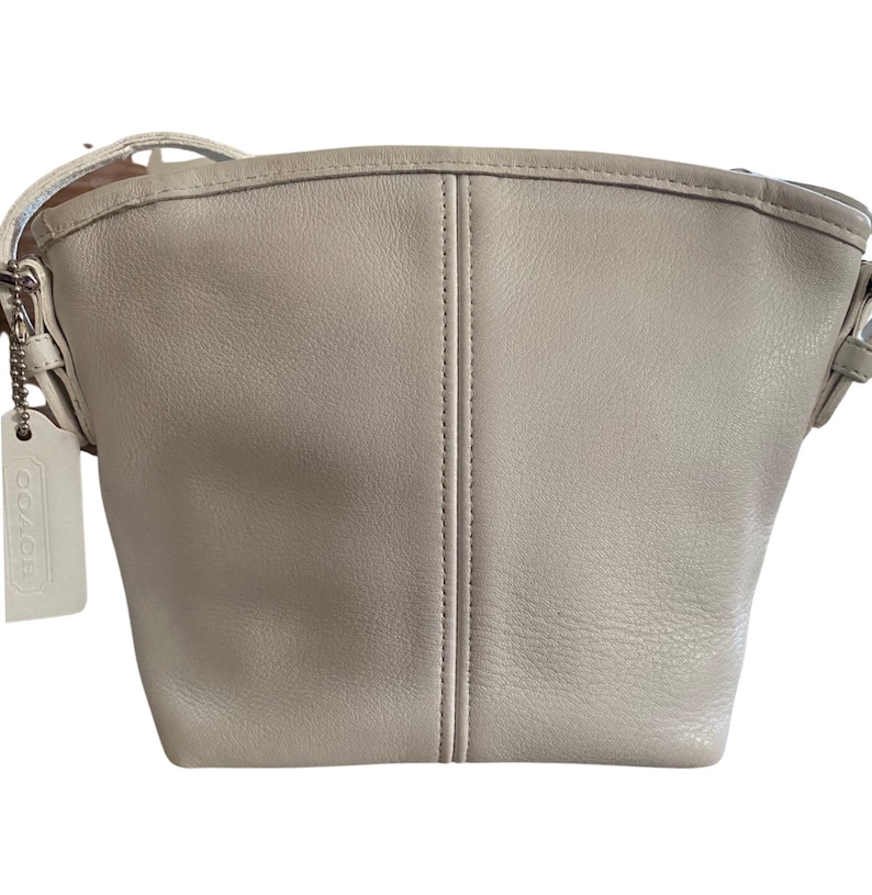 May include: A white leather shoulder bag with a Coach logo tag.