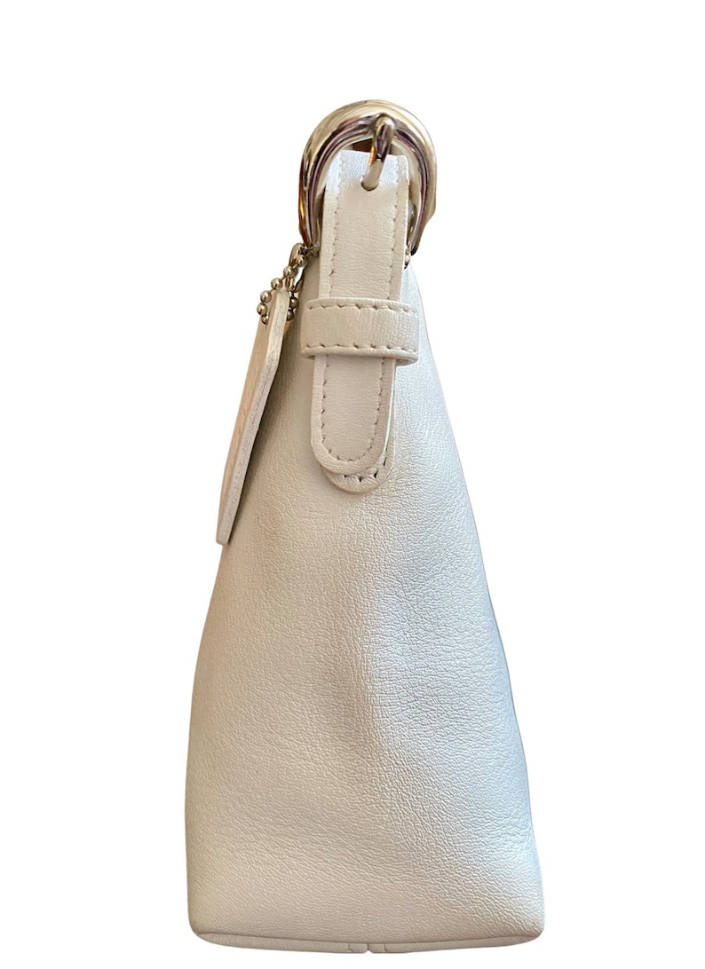 May include: A white leather handbag with a silver buckle and strap. The bag has a small, rectangular pocket on the front.