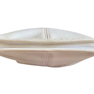 May include: A white leather handbag with a zipper closure. The bag is closed and the zipper is visible.
