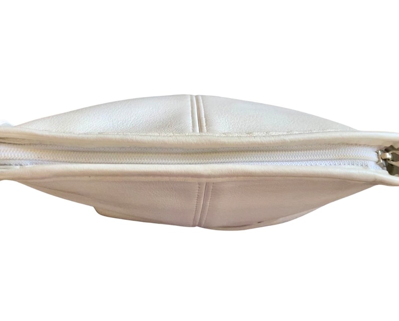 May include: A white leather handbag with a zipper closure. The bag is closed and the zipper is visible.