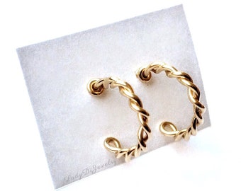 May include: A pair of gold-toned twisted hoop earrings. The earrings are displayed on a white card with the text "Lady Di Jewelry".