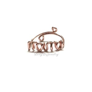 May include: A rose gold wire ring with the word "mama" spelled out in wire.