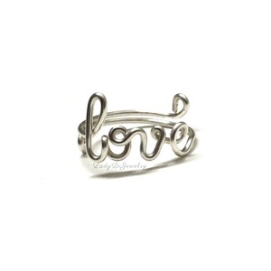 May include: Silver ring with the word "love" written in cursive.