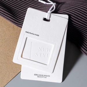 May include: White paper hang tag with a raised square frame that says "NEW STYLE" inside. The tag also says "Hello, Fashion World!" and "EXCLUSIVE DESIGN NEW STYLE".