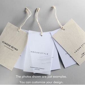 Könnte beinhalten: Drei Stoff-Hängeetiketten mit befestigter Schnur. Die Etiketten sind beige und weiß mit schwarzem Text. Der Text auf den Etiketten lautet "Classic Retro Cotton and Linen", "Vogue Style Fashion is not a form but attitude" und "Vogue Style Cotton and Linen Fashion is not a form but attitude".