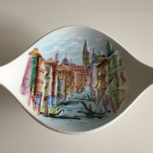Könnte beinhalten: Eine weiße Keramik-Schale in Blattform mit einem Reliefbild eines Kanals in Venedig, Italien. Das Bild zeigt farbenfrohe Gebäude, Gondeln und einen blauen Himmel.