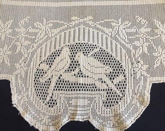 May include: Cream-colored, open-weave lace curtain with a detailed design. The central motif features two birds perched on a branch within a circular pattern. Floral and geometric patterns frame the birds, creating an elegant, vintage aesthetic.