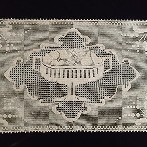 May include: A white crocheted doily with a delicate floral design in the center.