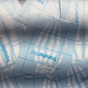 May include: Multiple sheets of clear transfer paper with a grid pattern. The paper has the text "TransferRite" printed on it.