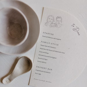 May include: A simple, elegant menu for a dinner party with a hand-drawn illustration of a couple and their dog. The menu features a starter, family-style dishes, and a dessert bar. The text reads "To Dine", "Starter", "Family-Style", "Dessert Bar", "Dinner by Night Kitchen", "Fennel and Watercress with Grapefruit", "Hanger Steak with Chimichurri", "Striped Bass with Turnip and Pickled Garlic Greens", "Jicama and Mango", "Red Lentil Curry and Fried Eggplant", "Broccoli and Tahini", "Coconut Milk Rice", "Croquembouche (by Balthazar)", "Tea & Coffee".