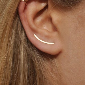 Smooth gold ear climber earring worn on ear, thin curved design for pierced ear