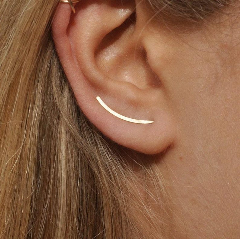 Smooth gold ear climber earring worn on ear, thin curved design for pierced ear