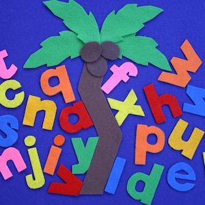May include: A felt craft featuring a palm tree with green leaves and a brown trunk, surrounded by colorful lowercase letters. The letters are in various colors, including pink, orange, yellow, and blue, on a blue background.