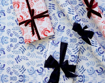 Può includere: Due scatole regalo rettangolari e due rotoli di carta da regalo con motivo floreale. Una scatola e un rotolo presentano fiori rossi e rosa su sfondo bianco con nastri rosso scuro. L'altra scatola e l'altro rotolo hanno fiori blu su bianco.