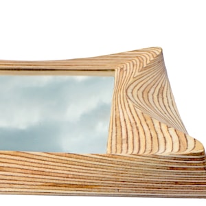 May include: A wooden picture frame with a wavy, organic design. The frame is made of light wood with a natural grain pattern. The frame is empty and ready to hold a picture.