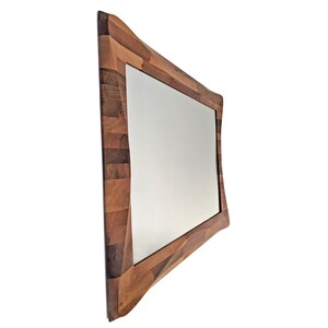 May include: A rectangular mirror with a unique, wavy, wooden frame made of different shades of brown wood.