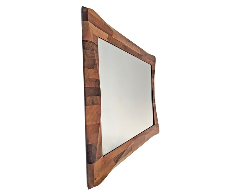 May include: A rectangular mirror with a unique, wavy, wooden frame made of different shades of brown wood.