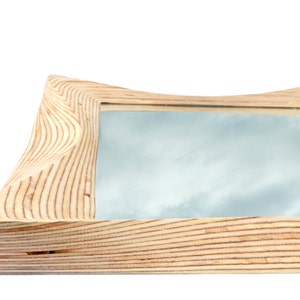 Pode incluir: Uma moldura de madeira com um design ondulado e org&acirc;nico. A moldura &eacute; feita de madeira clara com um padr&atilde;o de gr&atilde;o natural. A moldura est&aacute; vazia e pronta para conter uma foto ou um espelho.