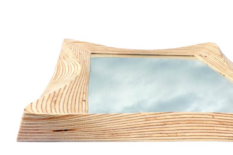 Pode incluir: Uma moldura de madeira com um design ondulado e org&acirc;nico. A moldura &eacute; feita de madeira clara com um padr&atilde;o de gr&atilde;o natural. A moldura est&aacute; vazia e pronta para conter uma foto ou um espelho.
