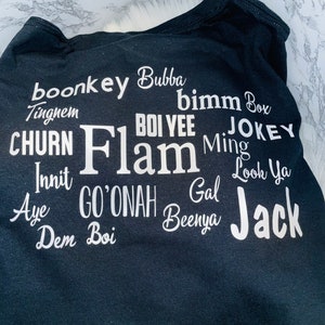 May include: Black t-shirt with white text that reads "boonkey Bubba", "Tingnem", "CHURN", "Innit", "Aye", "Dem Boi", "bimm Box", "BOI YEE", "JOKEY", "Flam", "Ming", "Gal", "GO'ONAH", "Beenya", "Look Ya", and "Jack".