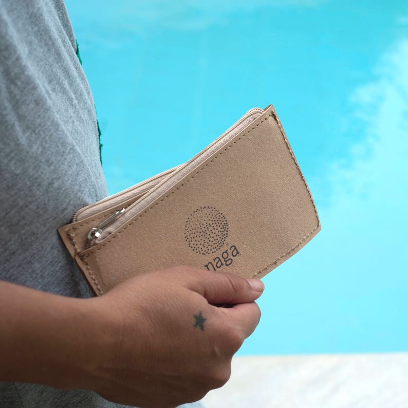 May include: A beige zippered pouch with a circular logo that says "naga" in black text.
