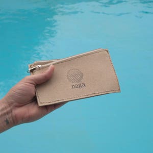May include: A brown cardboard zippered pouch with a logo that says "naga" and a circle design.