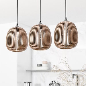 Pode incluir: Três luzes pendentes de madeira com um design de ripas penduradas no teto em uma cozinha moderna. As luzes são marrons e têm um acabamento de madeira natural.