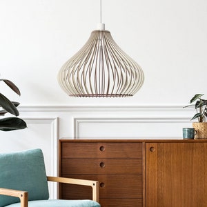 Könnte beinhalten: Eine weiße und braune Holz-Pendelleuchte hängt von der Decke in einem Raum mit einem hellblauen Sessel, einem Holzschrank und zwei Topfpflanzen.