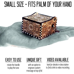 May include: A small wooden music box with a intricate geometric pattern on the lid. The music box is being held in a hand, demonstrating its size. The box has a hand crank on the side to play music. The text "EASY TO USE" is below the image, along with instructions to rotate the handle to play the tune. The text "UNIQUE GIFT" is below the image, along with instructions to engrave a custom message at the top of the lid. The text "VIDEO AVAILABLE" is below the image, along with instructions to look for details in the description to find a link to a video recording.