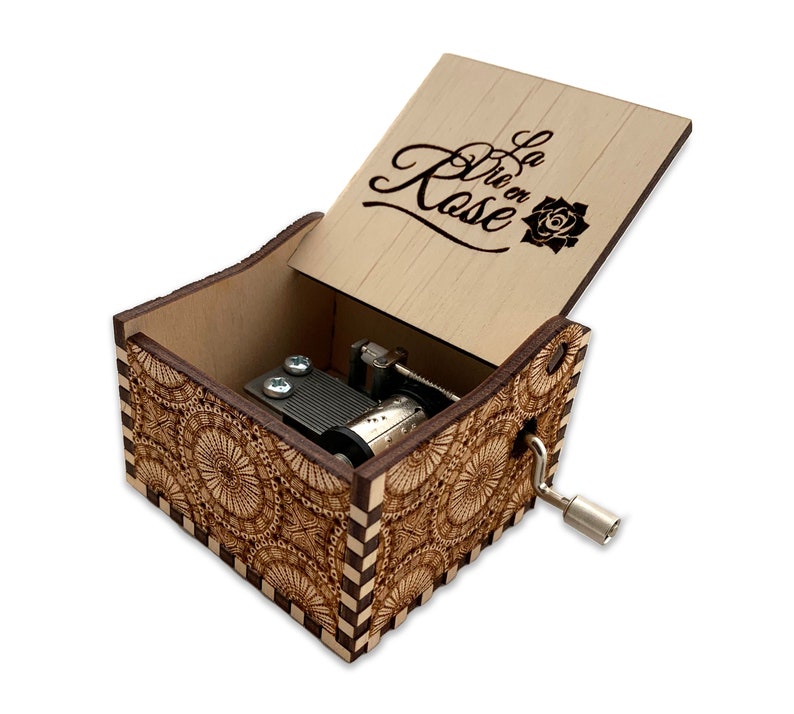 May include: Wooden music box with a floral design and the words "La Vie en Rose" engraved on the lid. The box is open and the music mechanism is visible.