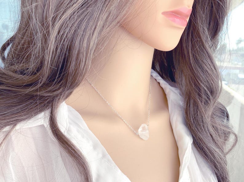 May include: A silver chain necklace with a clear, faceted crystal pendant.
