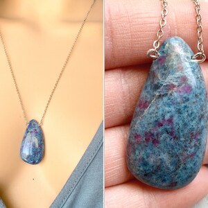 Op de afbeelding: Een zilveren ketting met een traanvormige hanger van blauwe en roze edelsteen.