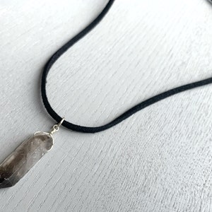 May include: A smoky quartz crystal pendant on a black suede cord necklace.