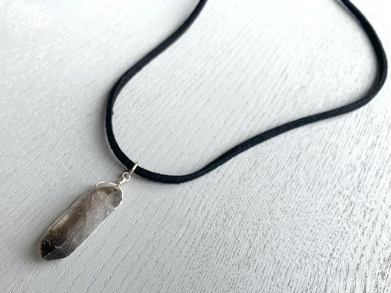 May include: A smoky quartz crystal pendant on a black suede cord necklace.