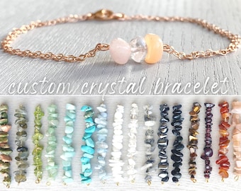 Peut inclure: Un bracelet à chaîne en or rose avec trois perles de cristal polies rose pâle, transparentes et pêche. En dessous, une collection de seize brins verticaux de divers éclats de pierres précieuses dans des tons de vert, bleu, blanc, gris, noir et orange.