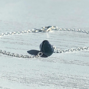 Peut inclure: Un bracelet &agrave; cha&icirc;ne fine en argent orn&eacute; d'une perle de pierre noire polie et irr&eacute;guli&egrave;re centr&eacute;e sur les maillons. Le bracelet est dot&eacute; d'un petit fermoir mousqueton en argent, pr&eacute;sentant un design simple et &eacute;pur&eacute;.